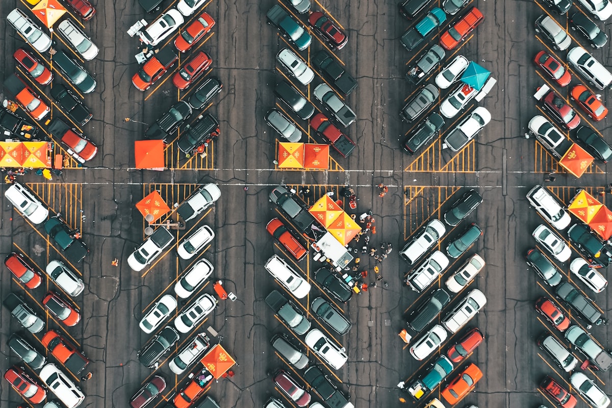 cars parked in a stadium tailgate lot with grills and coolers