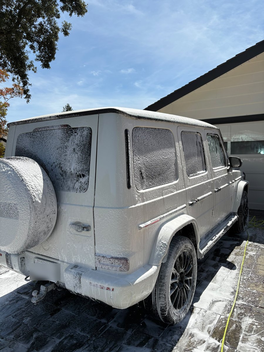 A white Mercedes-Benz G-Class covered in snow foam during an XN Car Detailing hand wash on a Bay Area driveway