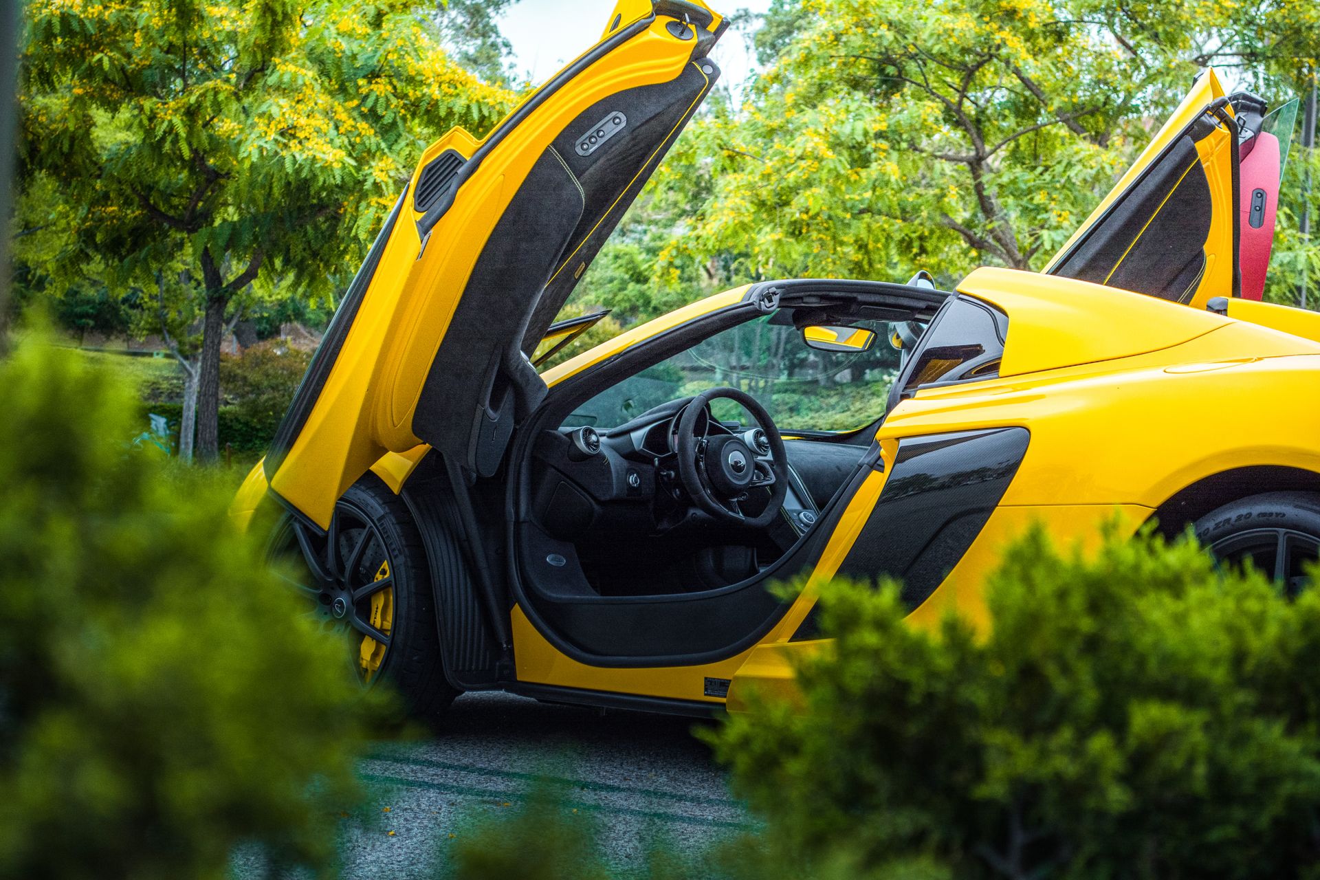 Yellow McLaren with its doors open, detailed to a showroom finish
